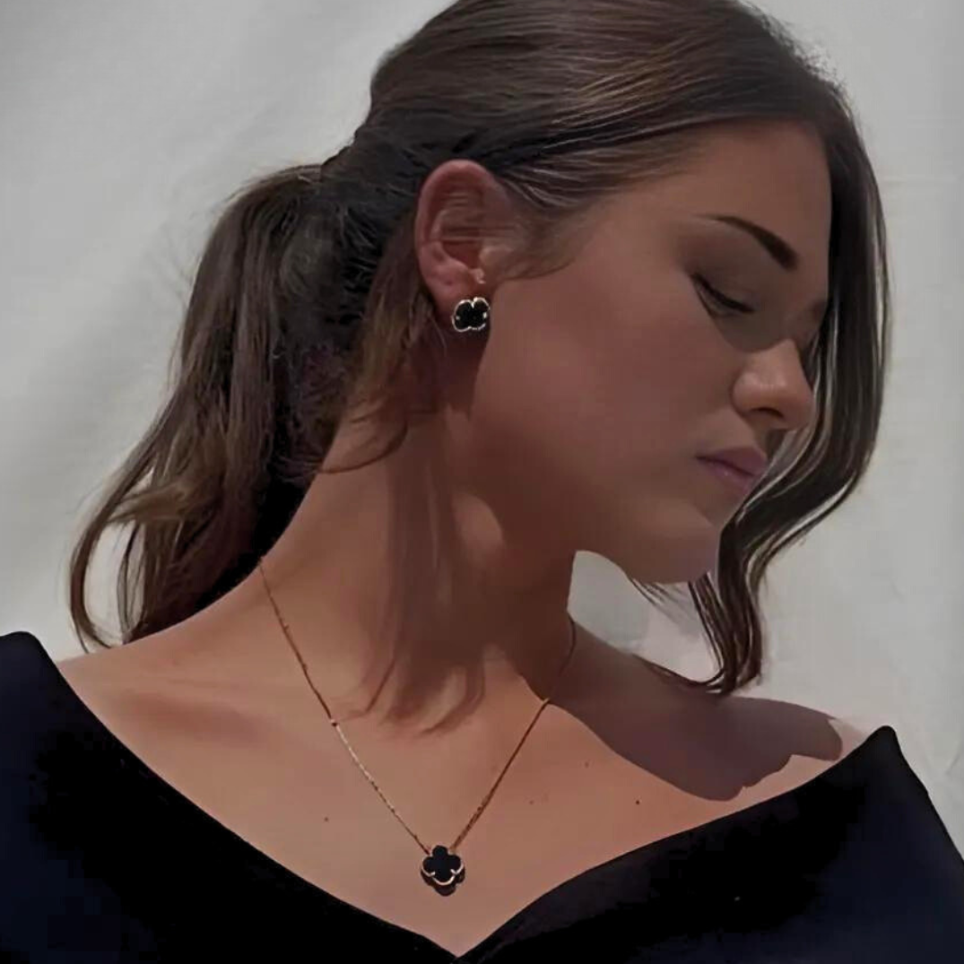 Woman wearing a black off-shoulder top and black earrings with a white background